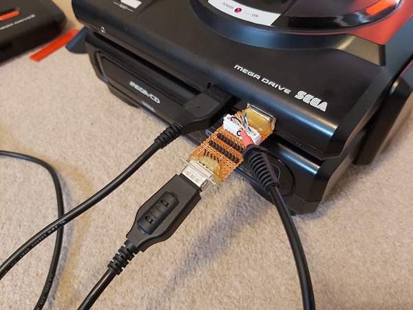 A DE-9 breakout adaptor attached to the second controller port of a Mega Drive